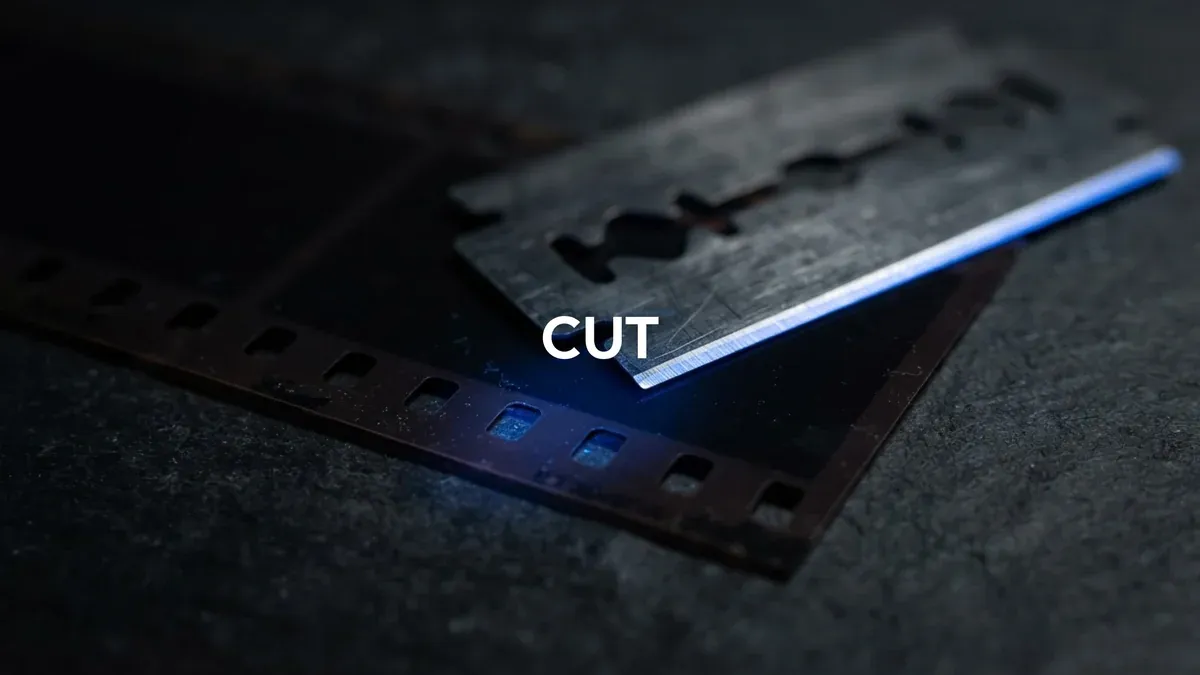 A razor blade resting on a strip of film against a near-black background with a blue light along its edge